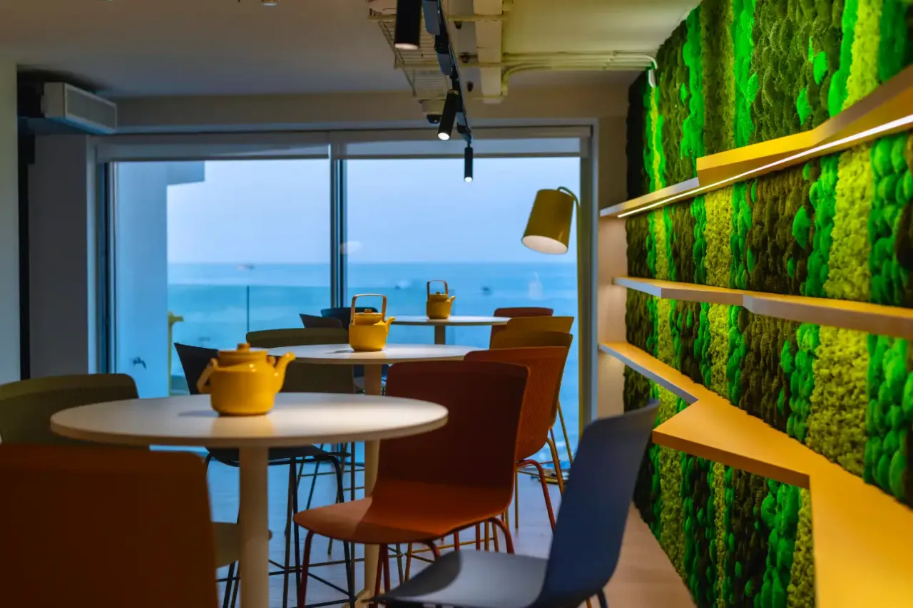 Smart Cow offices, Balluta Bay: a planted wall beside a table at a window over the sea